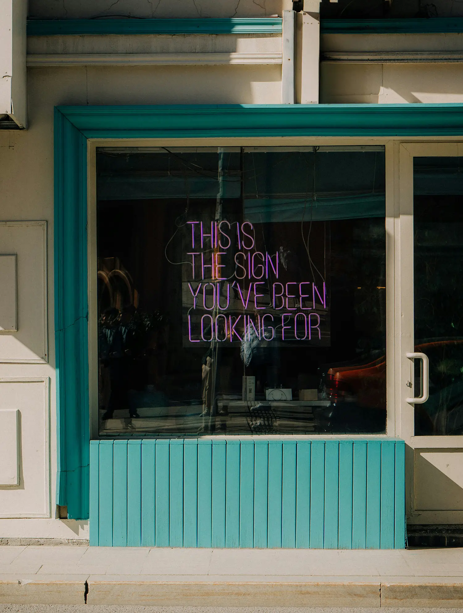 Photograph of a shop with a neon in the window with the words this is the sign you have been looking for